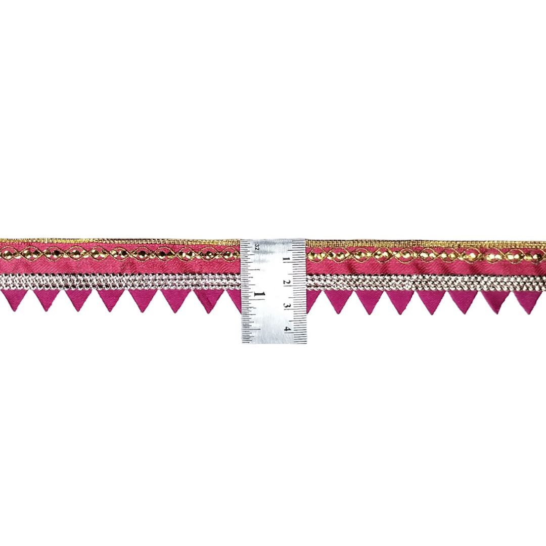 Decorative ribbon with pink and gold pattern next to a ruler for measurement on a white background