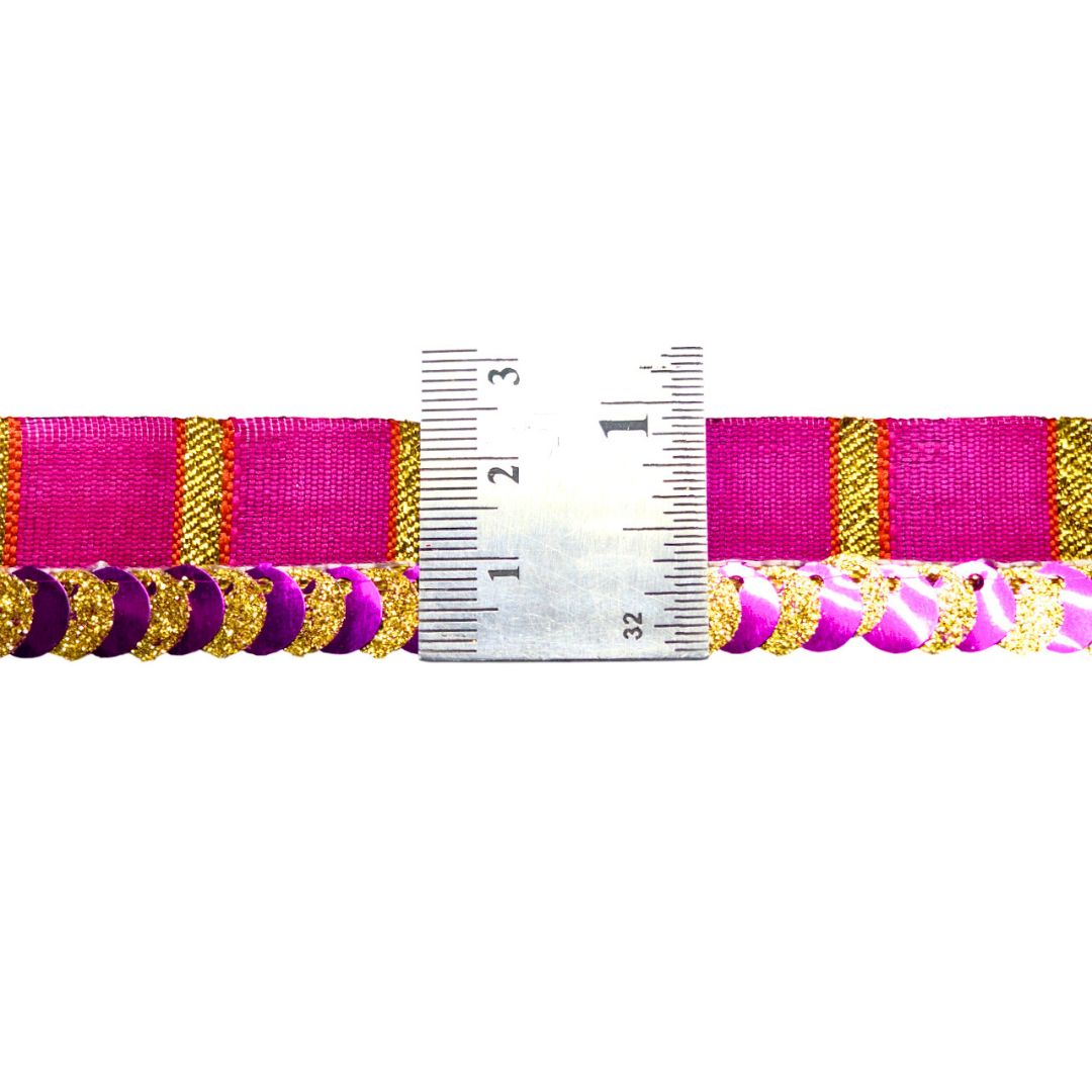 Pink and gold ribbon with a ruler for scale on a white background