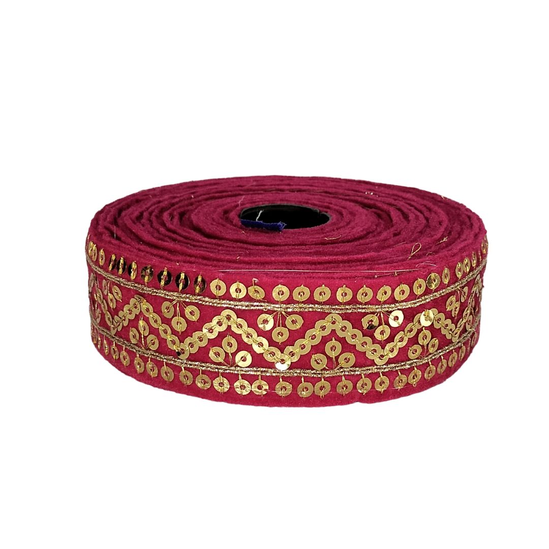 Roll of red ribbon with gold sequin pattern on a white background