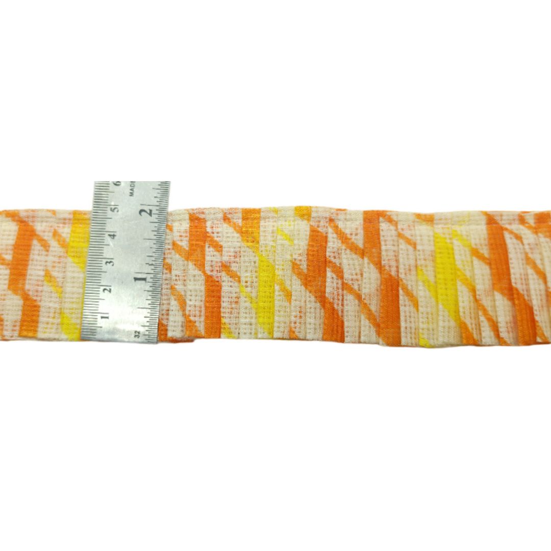 Strip of fabric with orange and yellow pattern next to a ruler on a white background