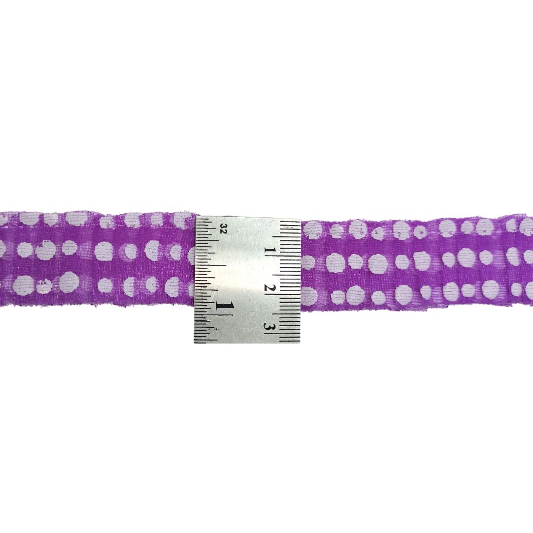 Purple ribbon with white polka dots and a ruler for scale on a white background
