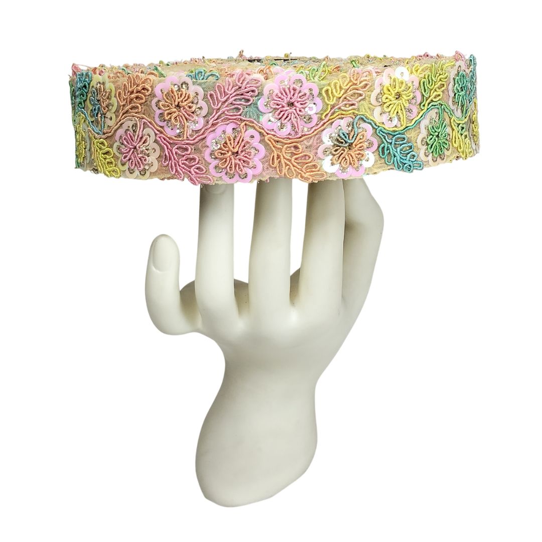 Decorative headband with floral patterns on a white mannequin hand