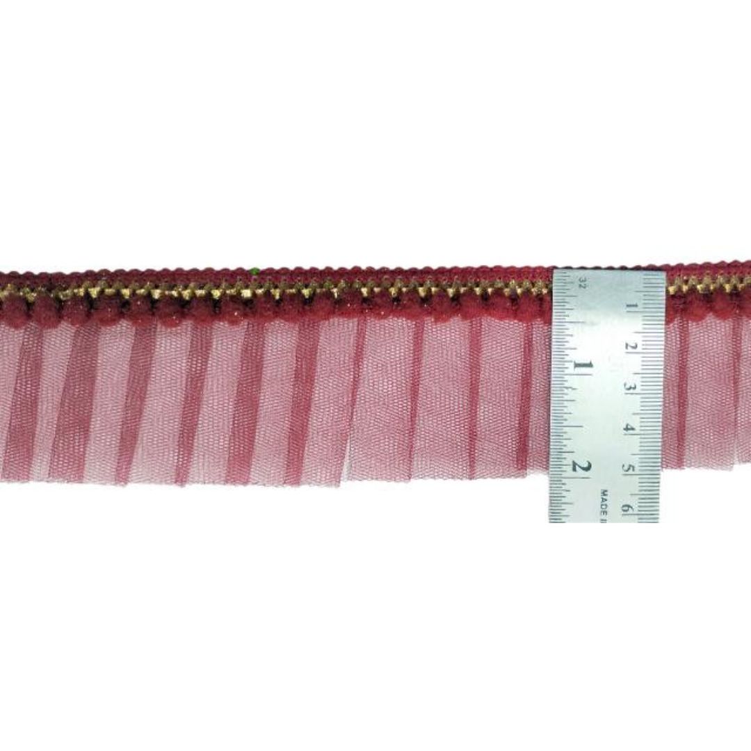 Pink mesh ribbon with gold trim and a ruler for measurement on a white background