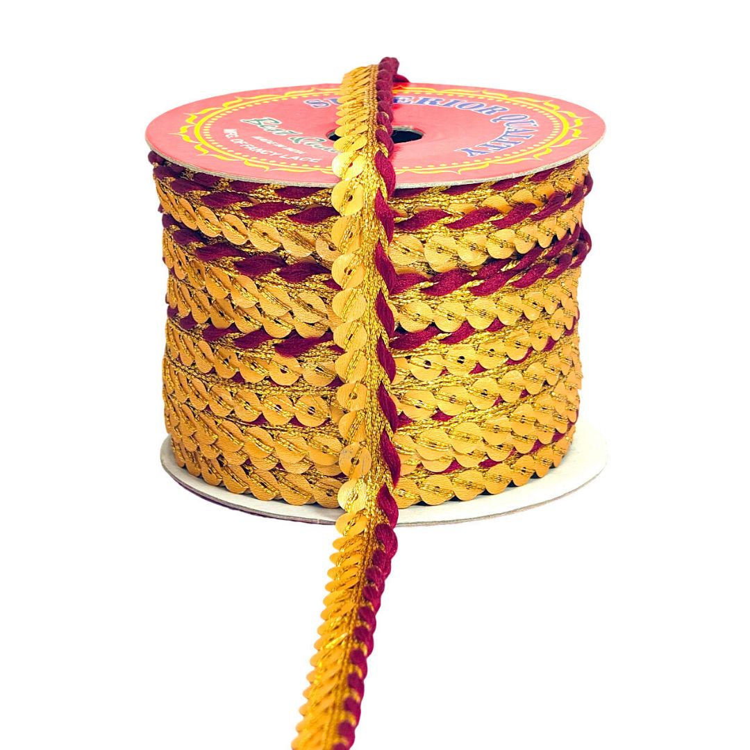 Spool of gold and red sequin ribbon on a white background