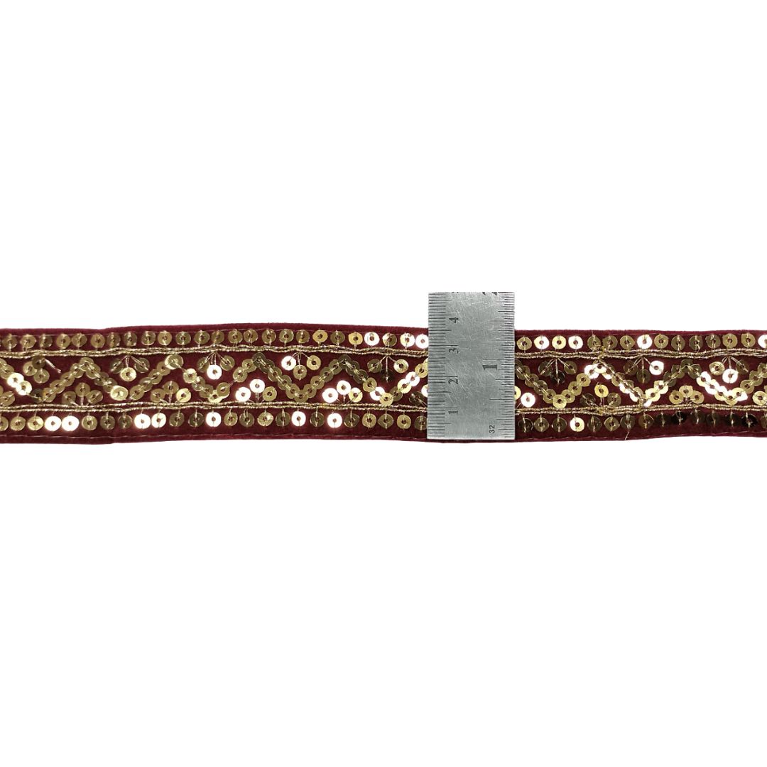 Decorative belt with gold sequins and a ruler for scale on a white background