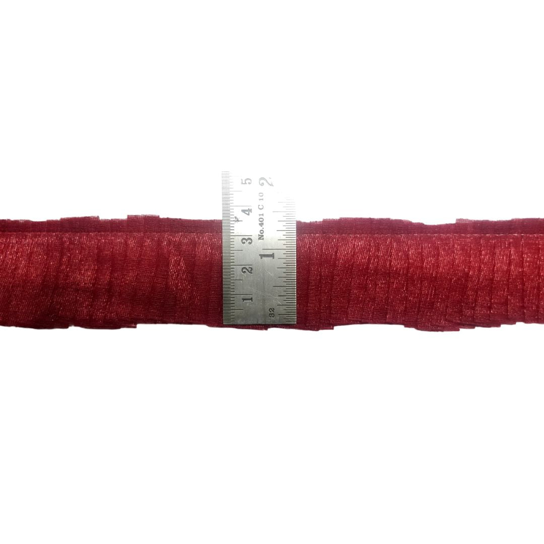 Red yarn roll with a silver ruler on a white background