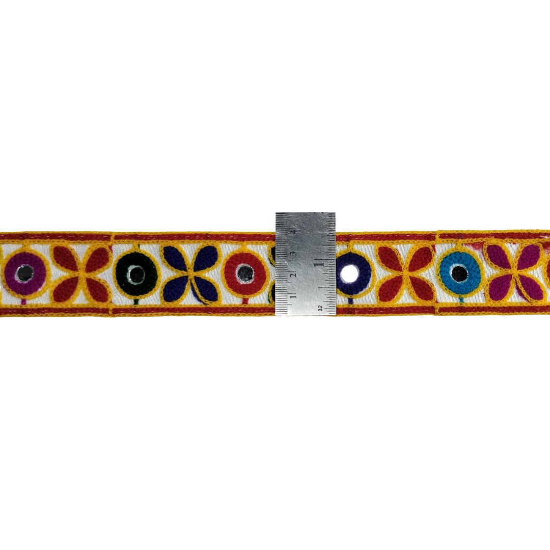 Decorative belt with floral patterns and a ruler for scale on a white background