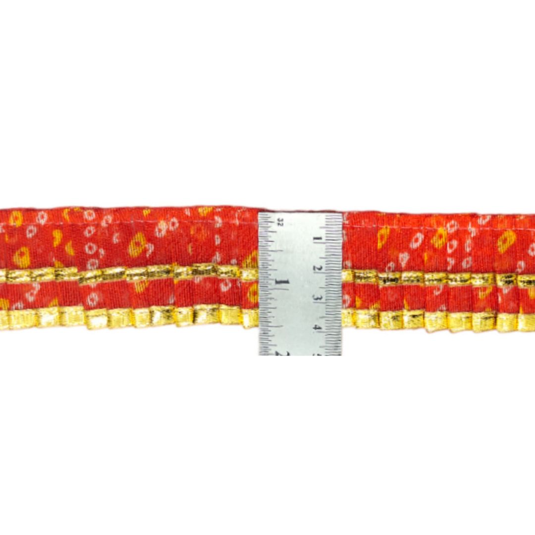 Red belt with gold accents and floral pattern, measured against a ruler on a white background