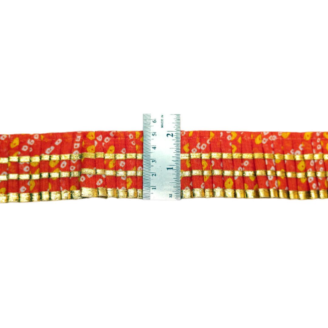 Red ribbon with gold patterns and a measuring tape for scale on a white background