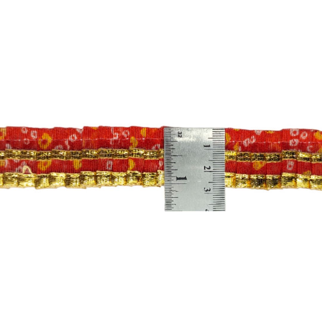 Red and gold woven belt with a ruler for scale on a white background