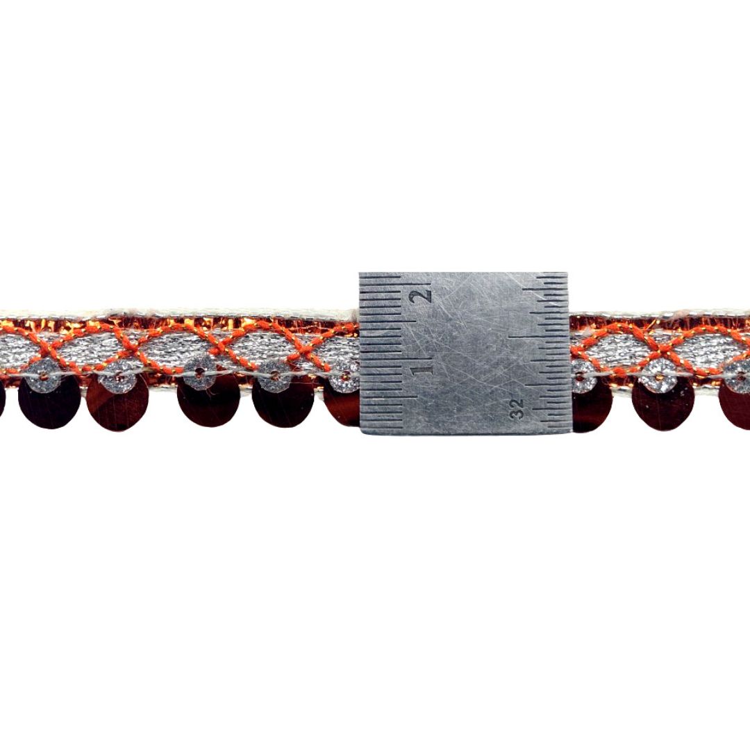 Close-up of a decorative trim with beads and a ruler for scale on a white background