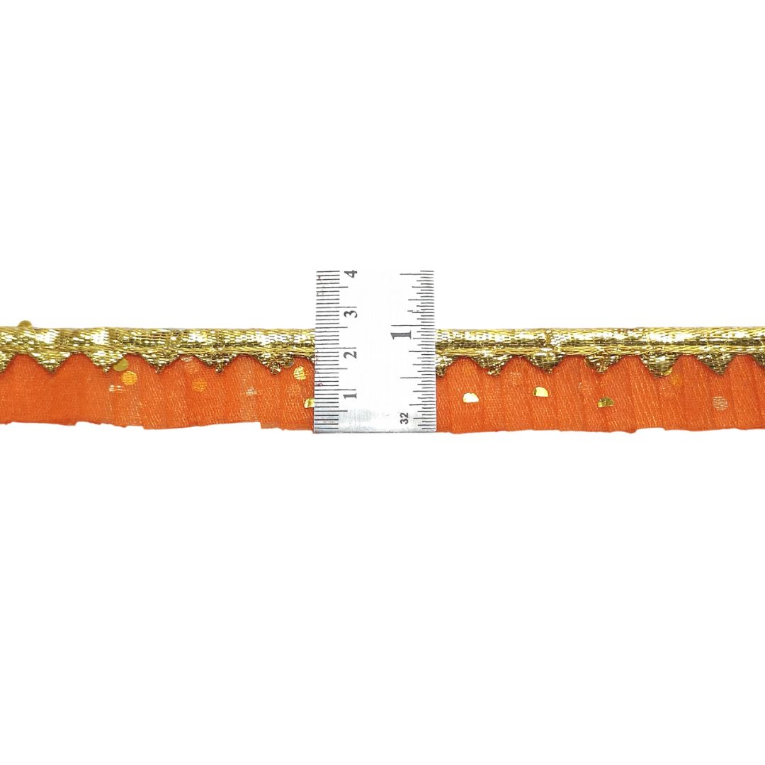 Orange fabric with gold lace trim and a ruler for scale on a white background