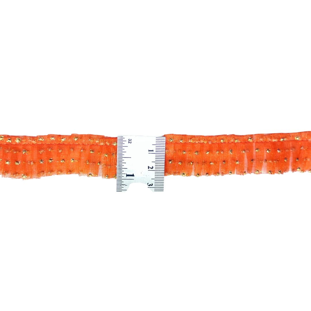 Orange rhinestone belt with a ruler for scale on a white background