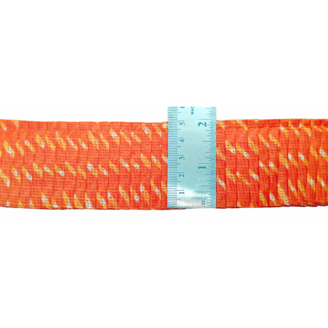 Orange fabric with white patterns and a blue ruler for scale on a white background