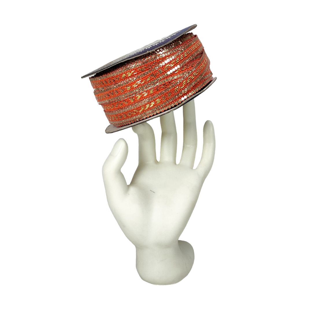 Spool of orange and silver ribbon on a mannequin hand against a white background