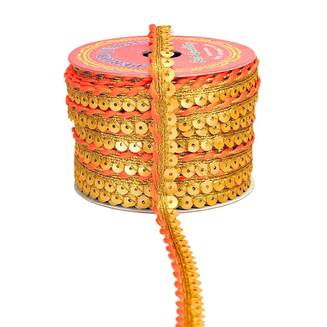 Spool of gold and orange sequin ribbon on a white background