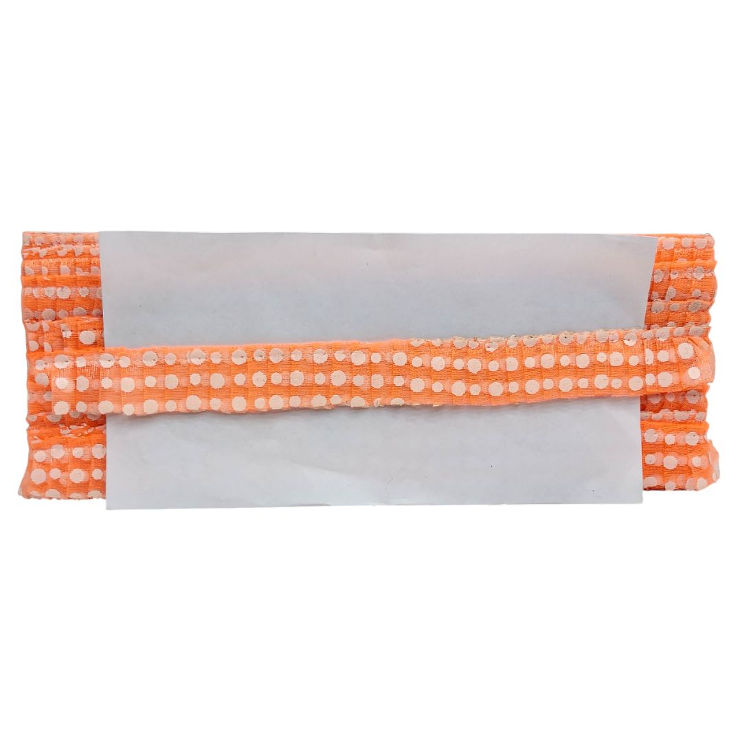 Folded orange fabric with white polka dots on a white background