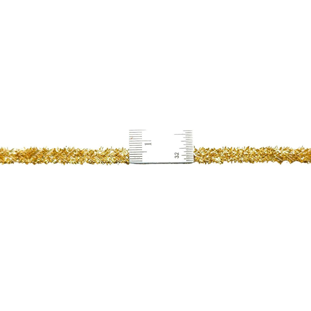 Gold bracelet with a ruler for scale on a white background
