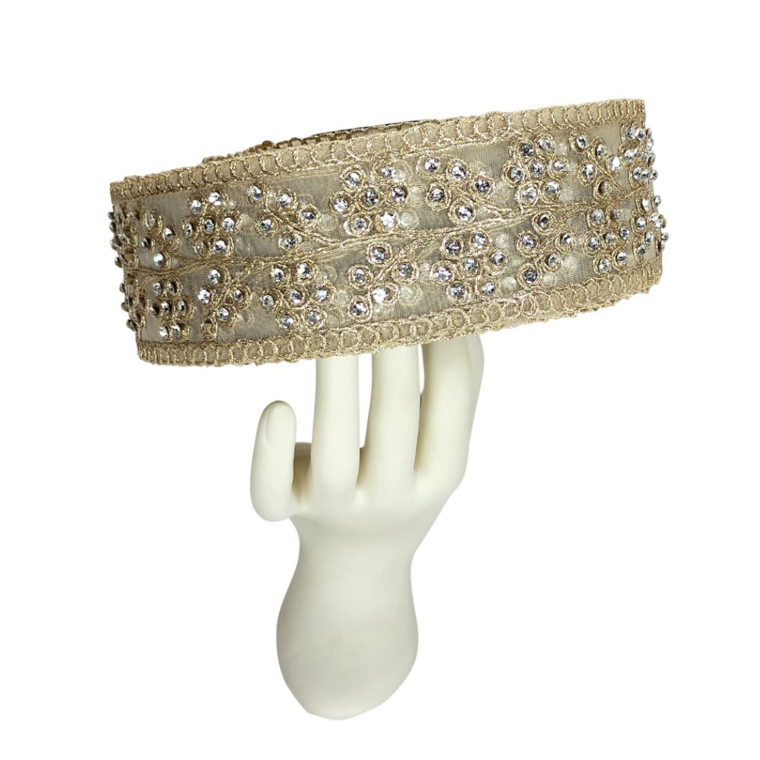 Decorative headband with crystals on a mannequin hand against a white background