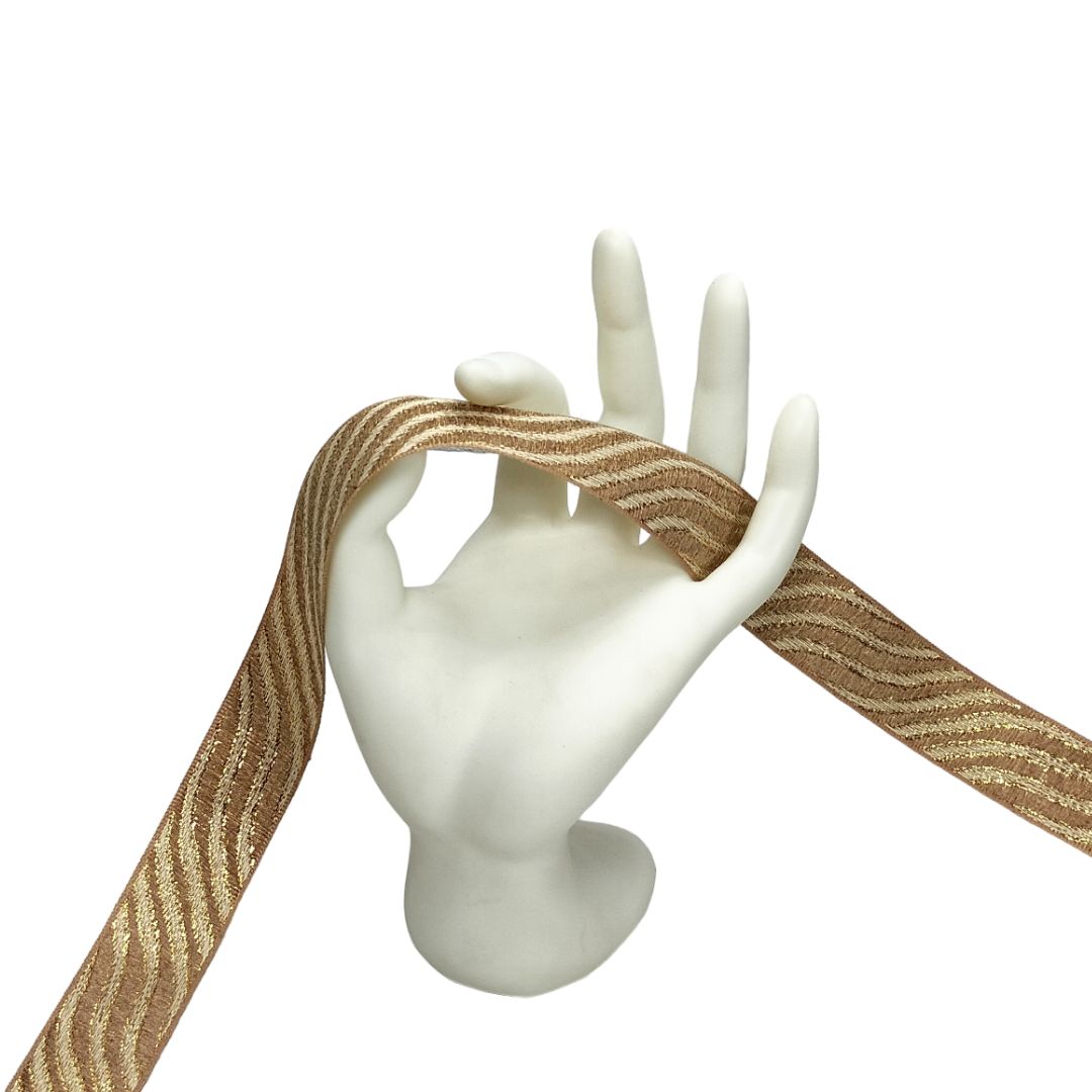 Mannequin hand holding a strip of gold and brown striped ribbon on a white background