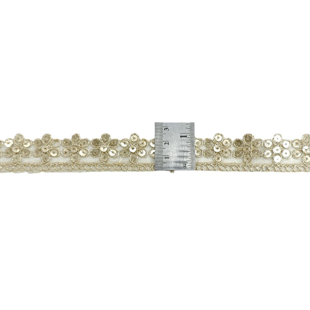 Decorative ribbon with beads and a measuring tape for scale on a white background