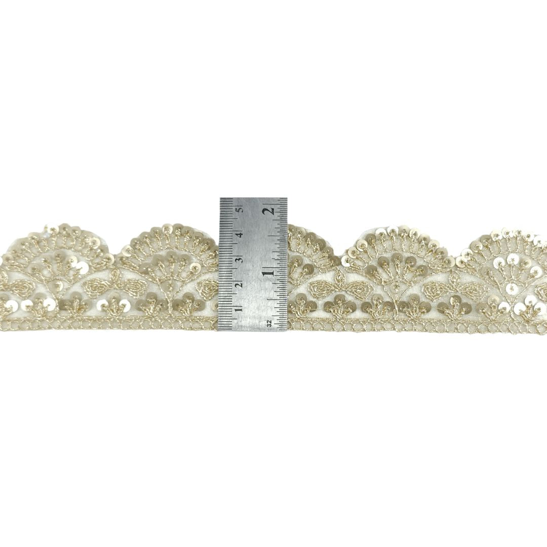 Decorative lace trim with a ruler for scale on a white background