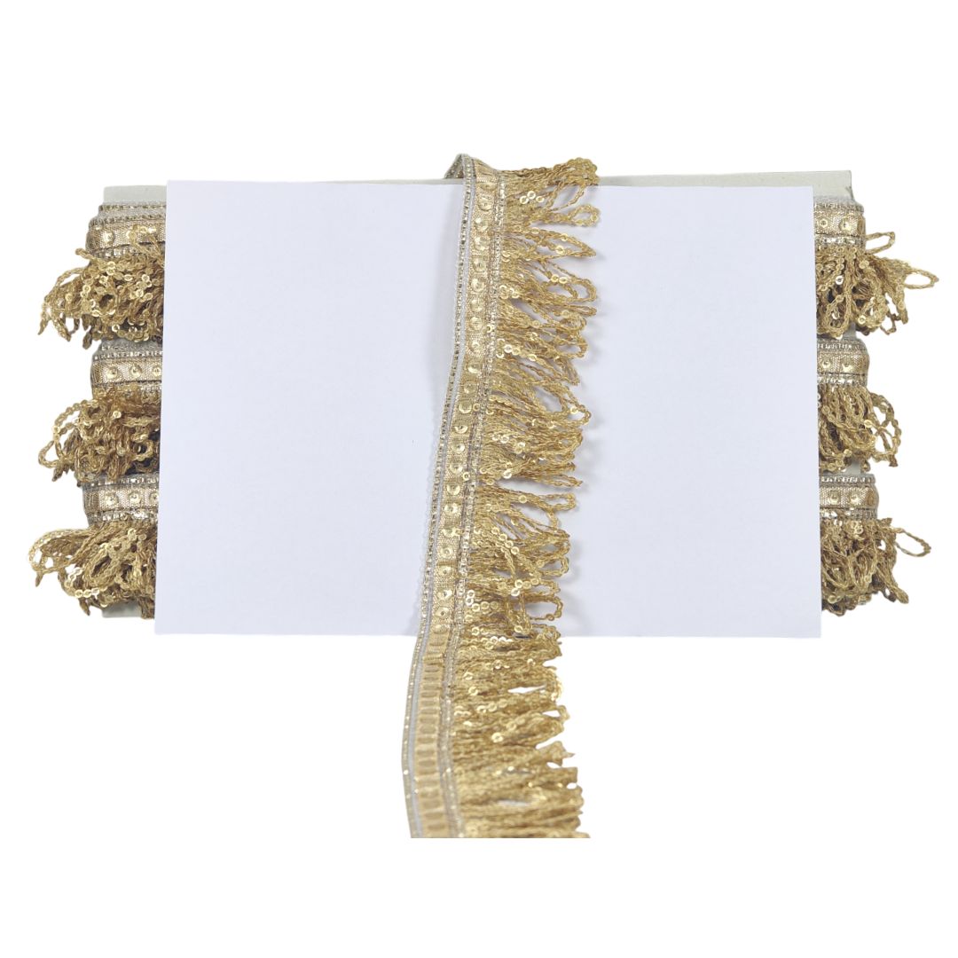 White fabric with gold fringe and sequin trim on a white background