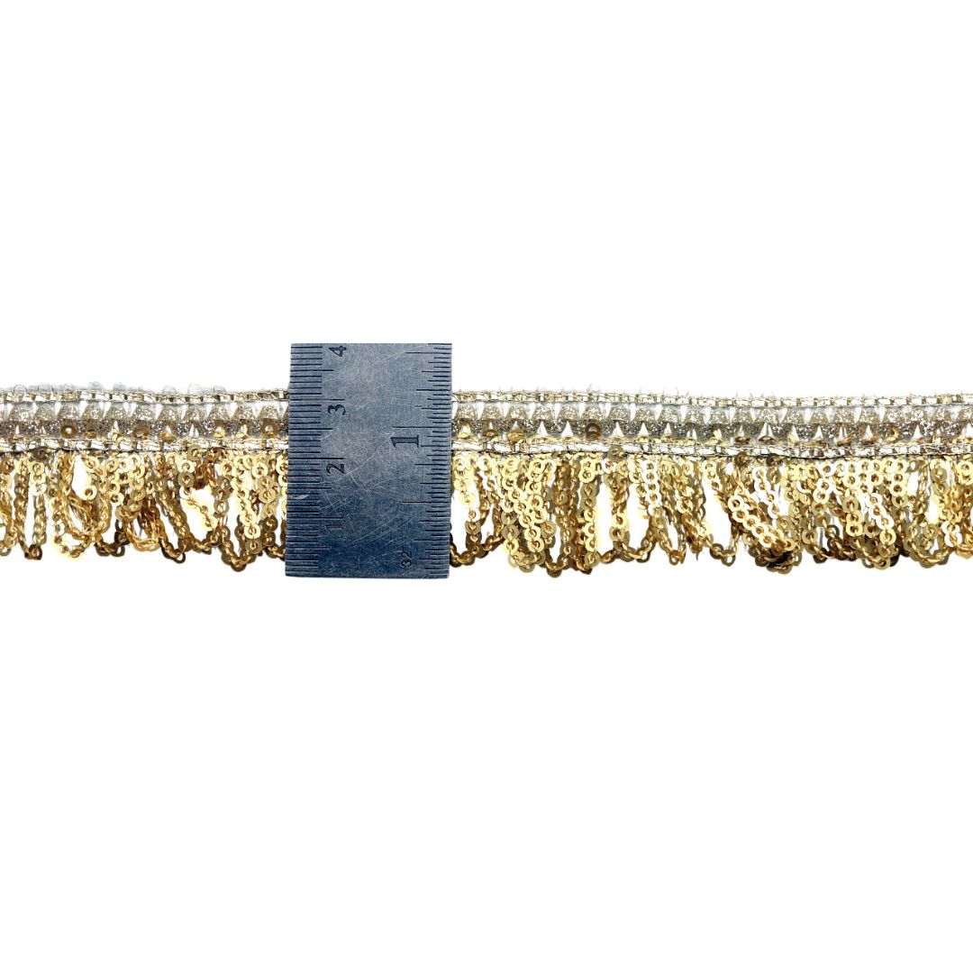 Gold fringe trim with a ruler for scale on a white background