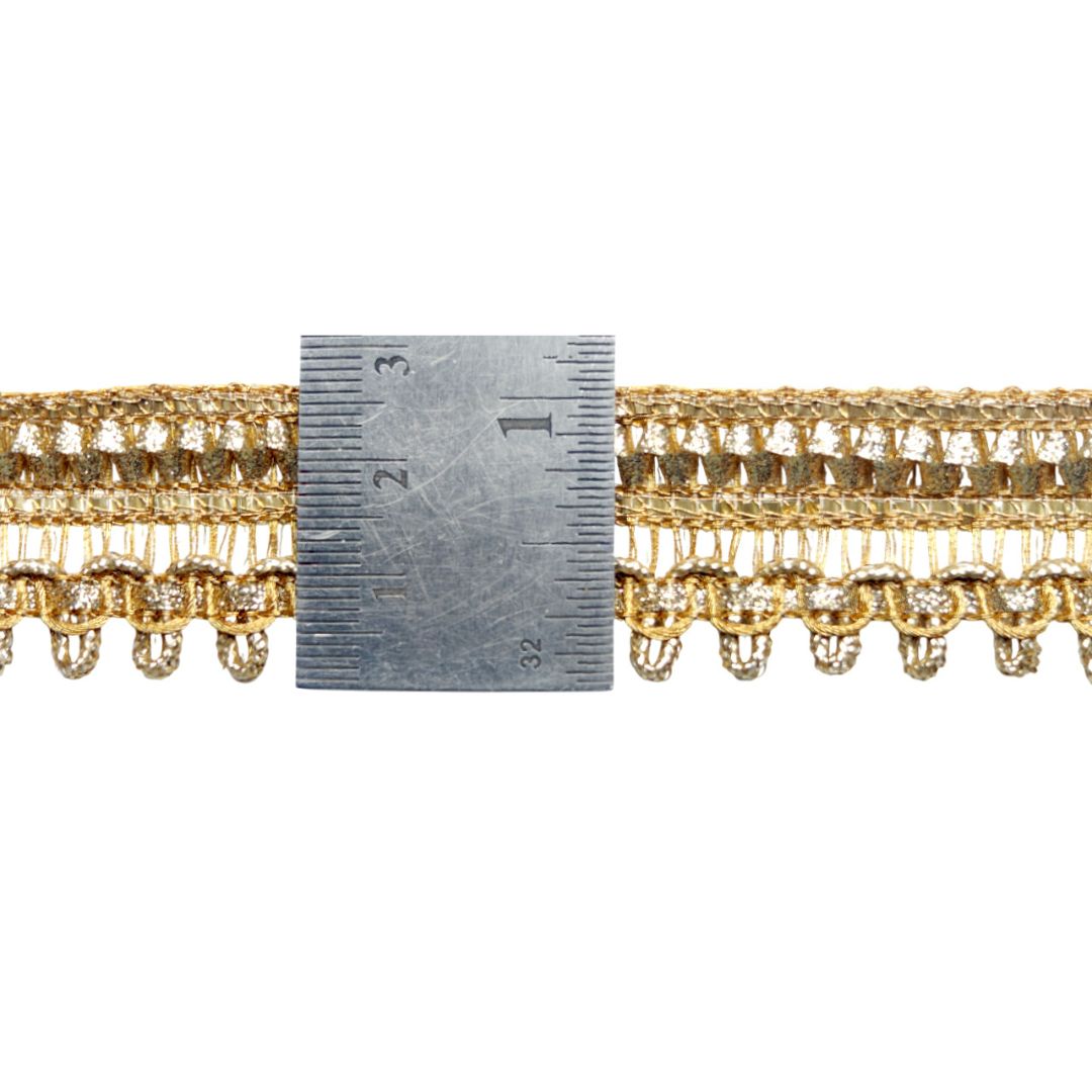 Gold lace trim with a ruler for scale on a white background