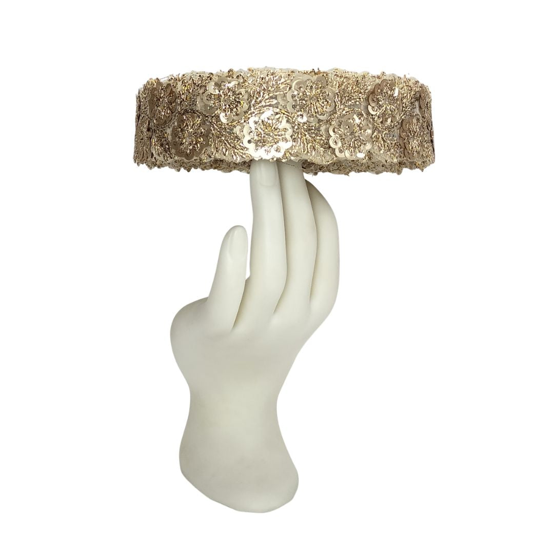 Decorative object resembling a hand holding a gold sequined top on a white background