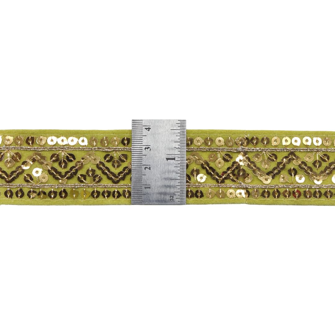 Decorative ribbon with gold and green pattern and a ruler for scale on a white background