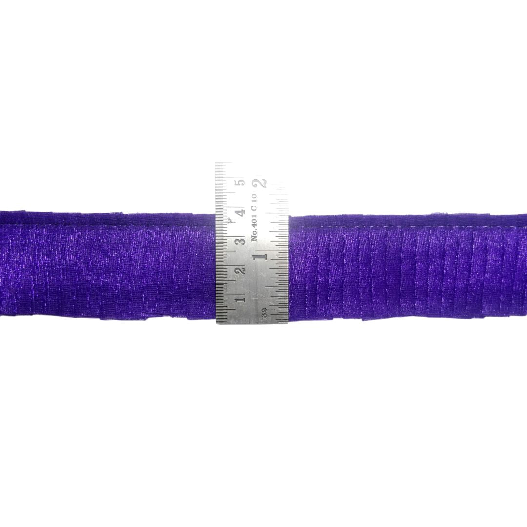 Purple thread spool with a ruler for scale on a white background