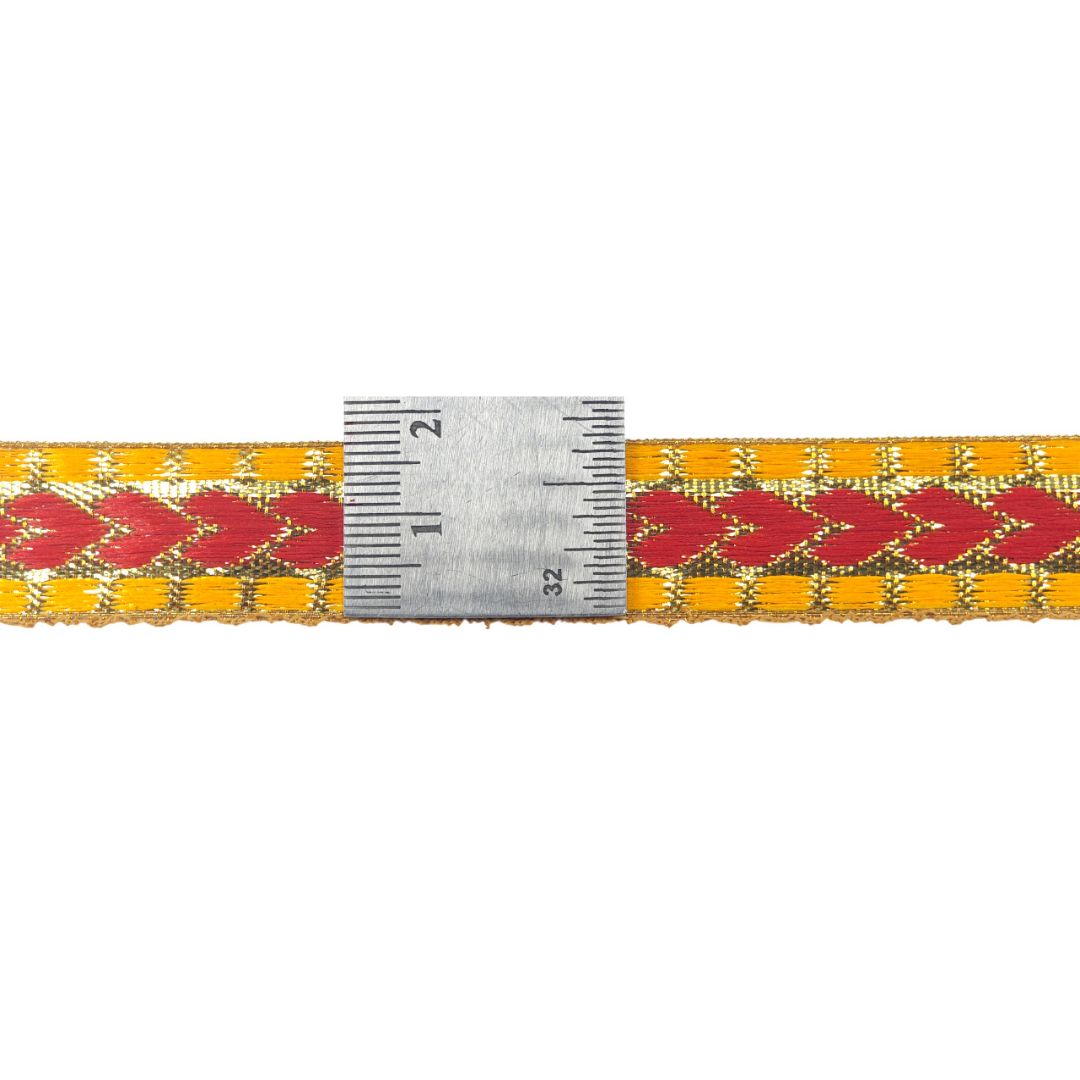 Woven belt with red and yellow pattern and a ruler for scale on a white background