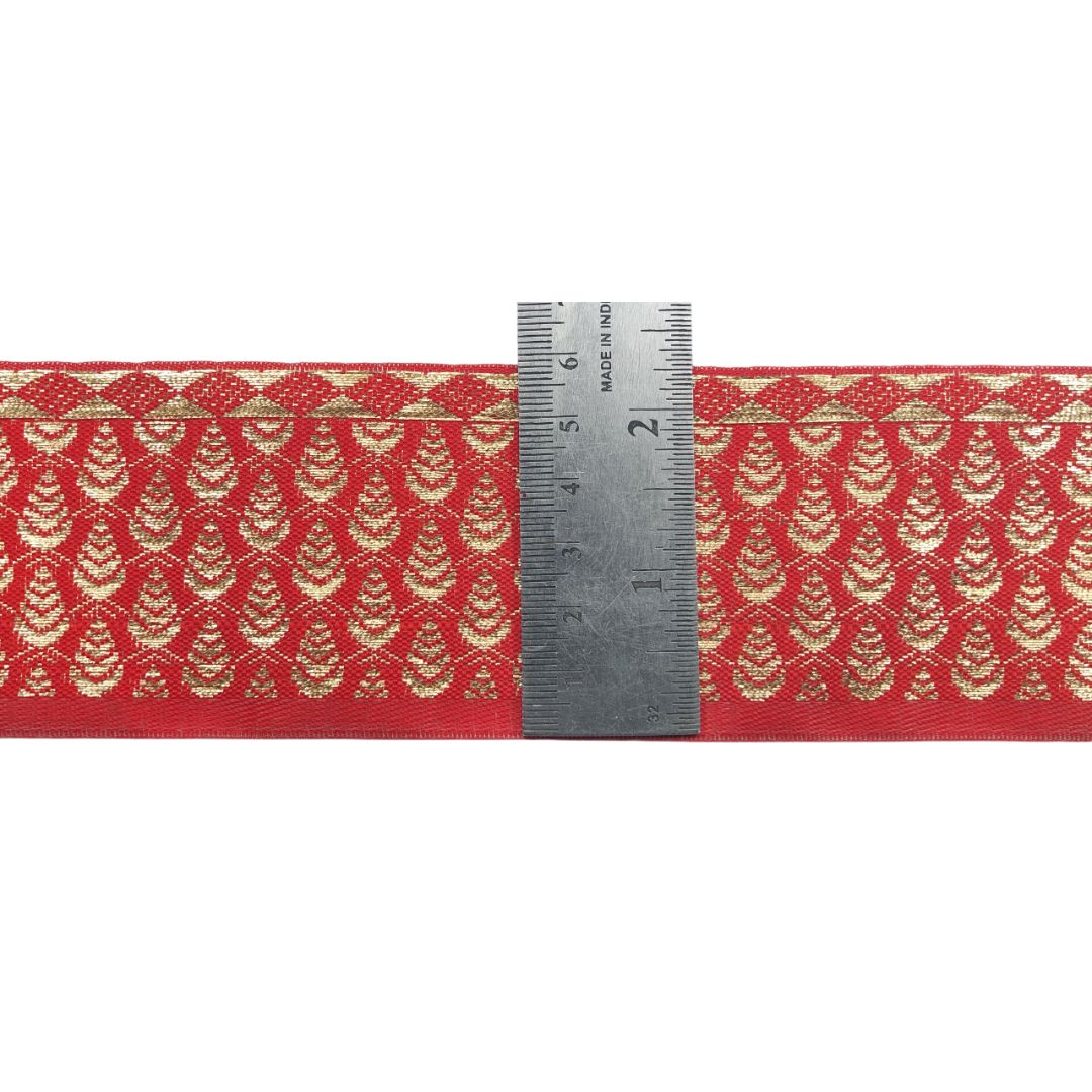 Red fabric with gold pattern and a ruler for scale on a white background