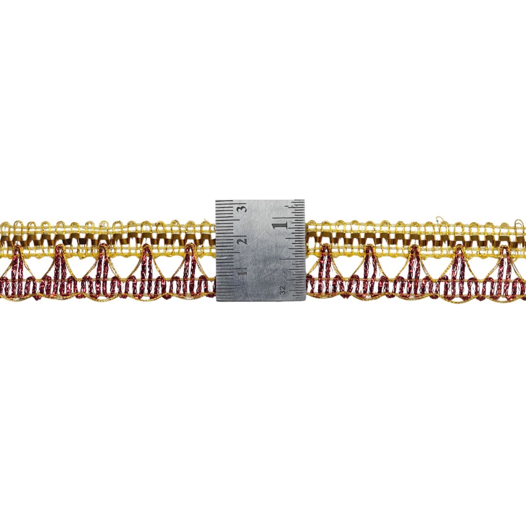 Gold and red lace trim with a ruler for measurement on a white background