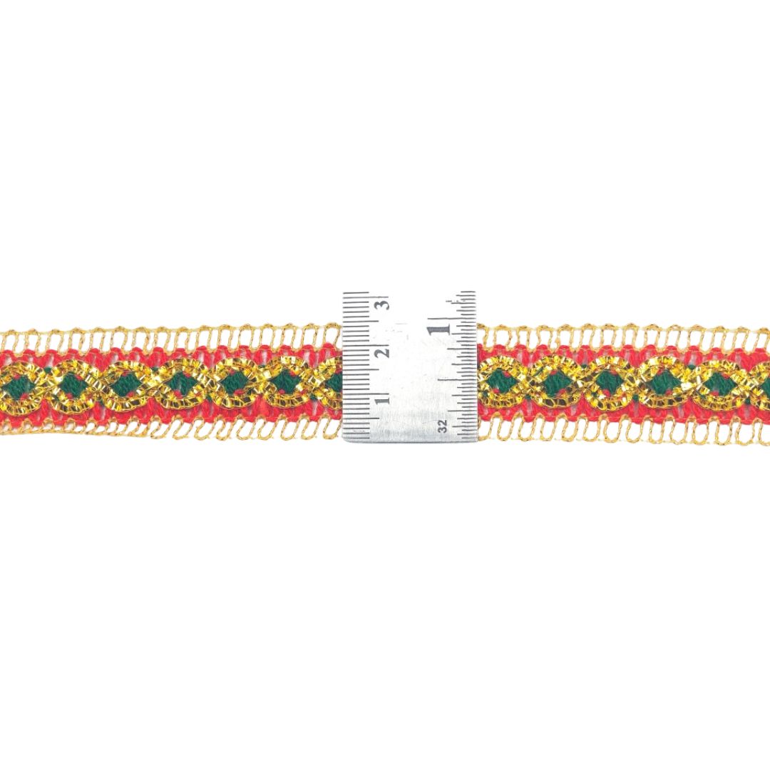 Decorative ribbon with gold, green, and red pattern next to a ruler on a white background