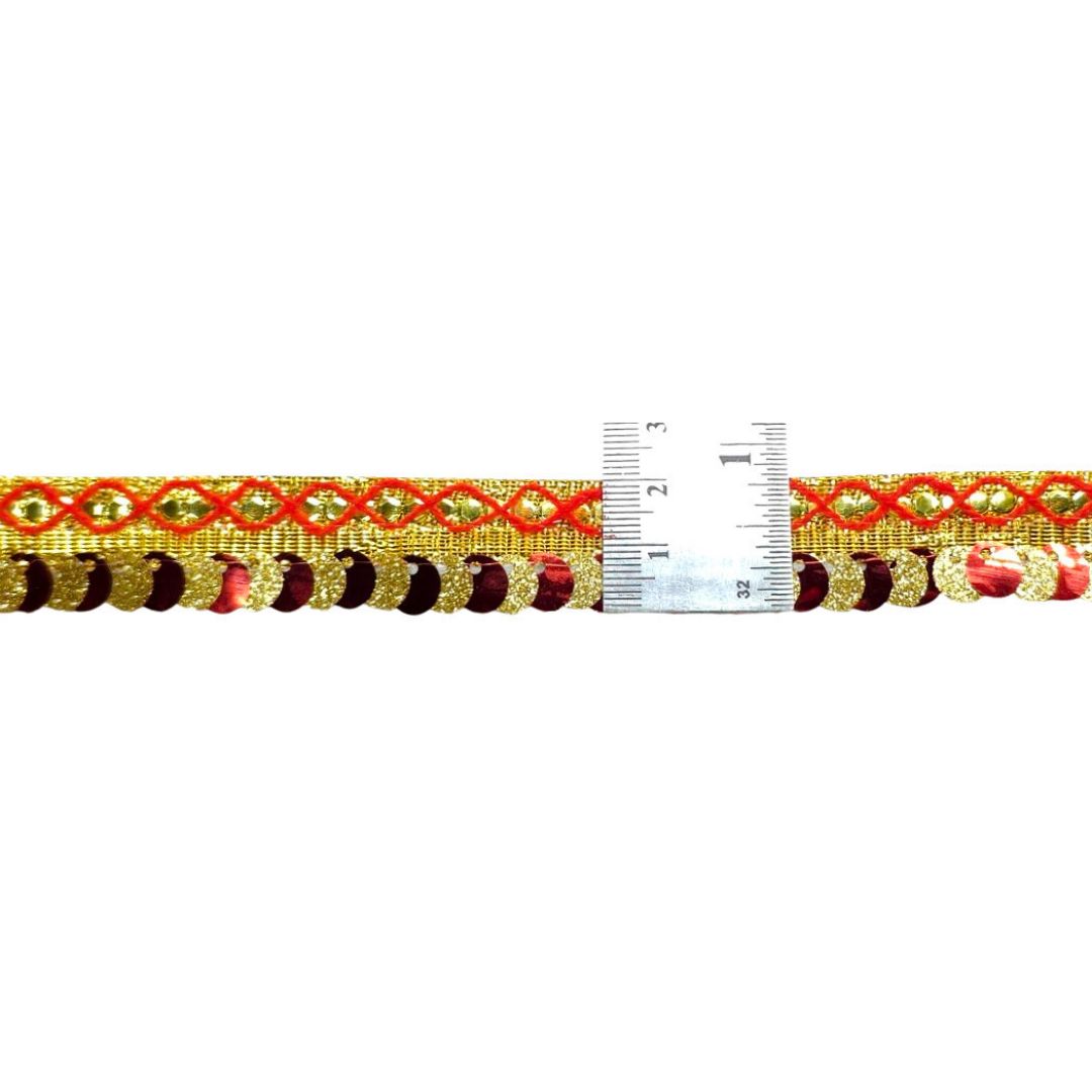 Decorative ribbon with gold and red pattern next to a ruler on a white background