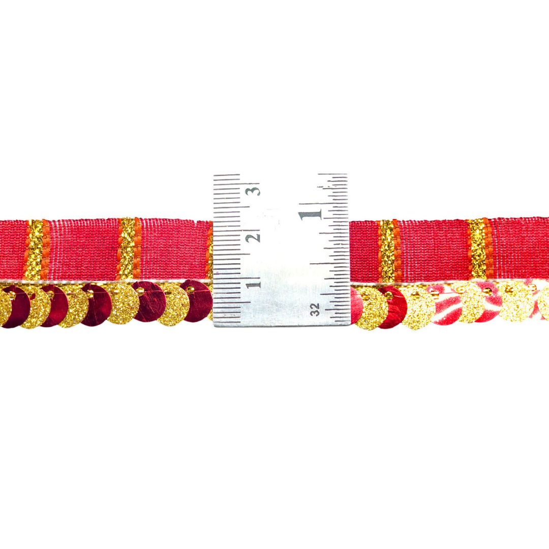 Red ribbon with gold fringe and a measuring tape for scale on a white background