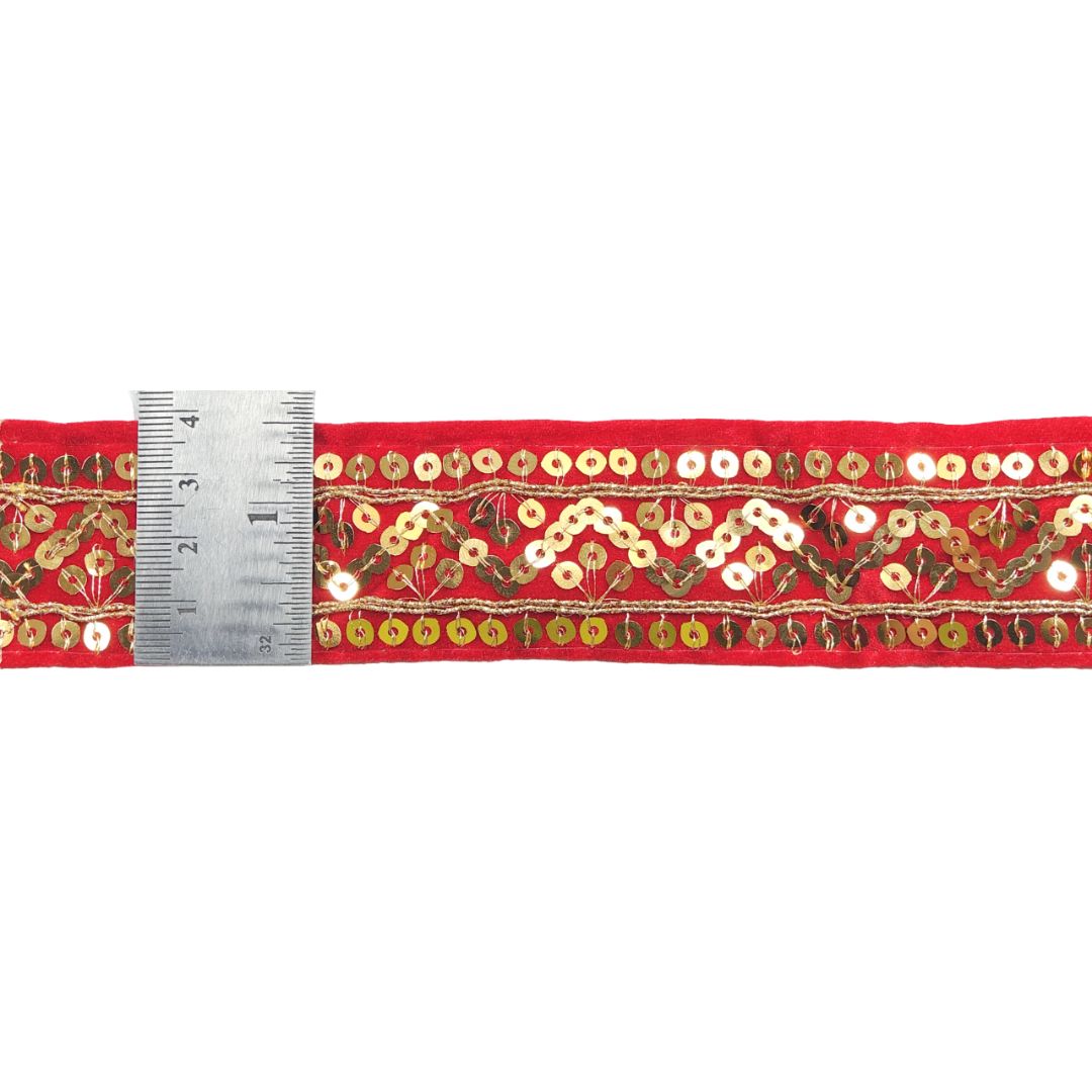 Red fabric strip with gold and white floral pattern and a ruler for scale on a white background