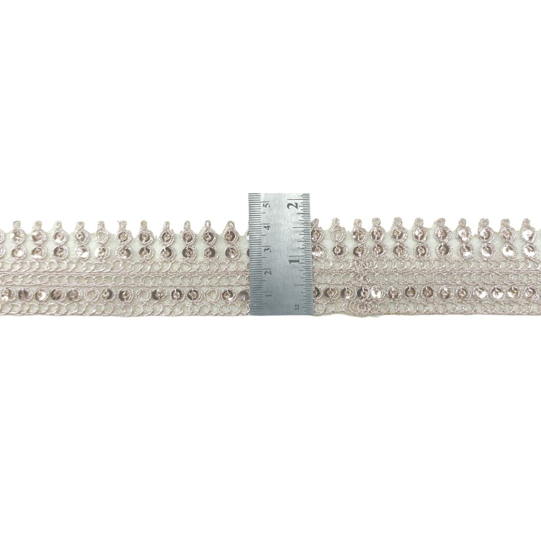 Decorative ribbon with beads and a ruler for scale on a white background