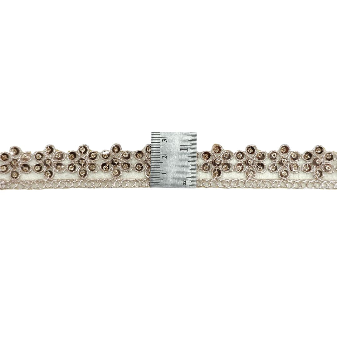 Decorative lace trim with beads and a ruler for scale on a white background