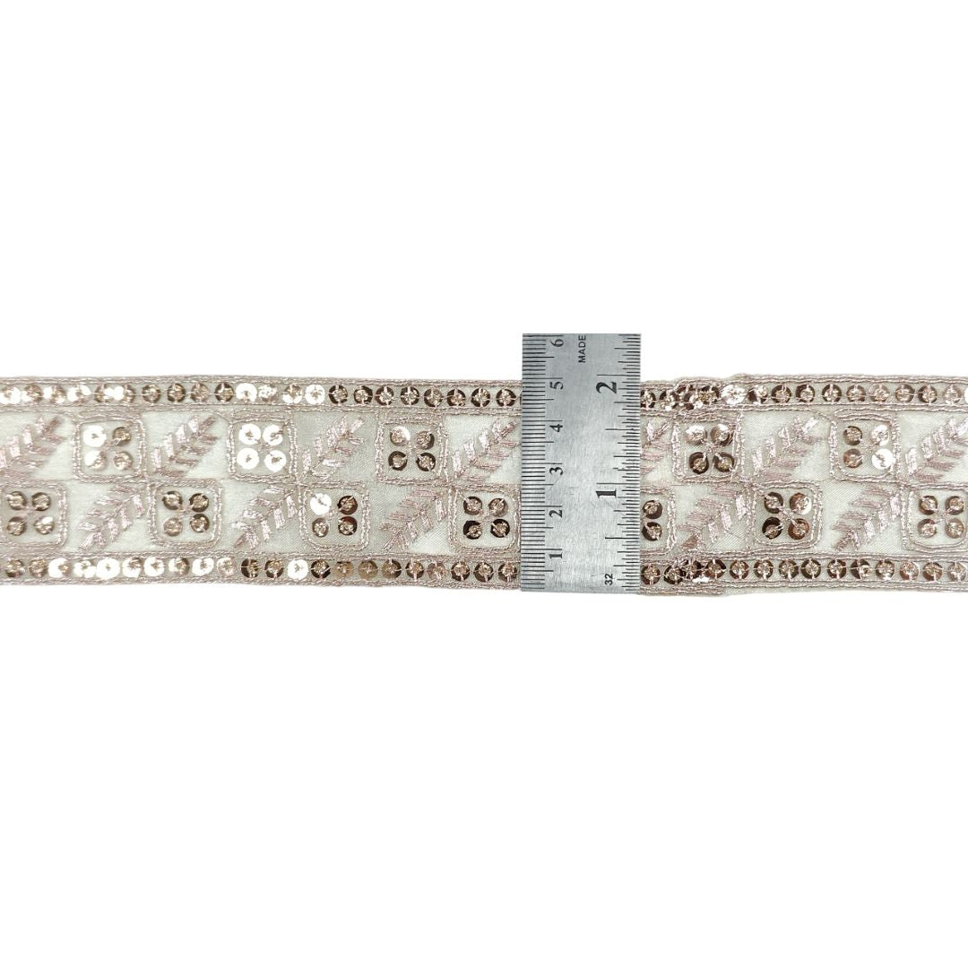 Decorative ribbon with sequins and beads measured against a ruler on a white background