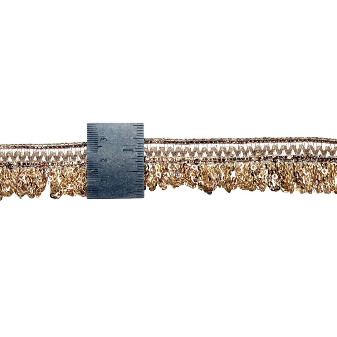 Gold fringe trim with a ruler for scale on a white background