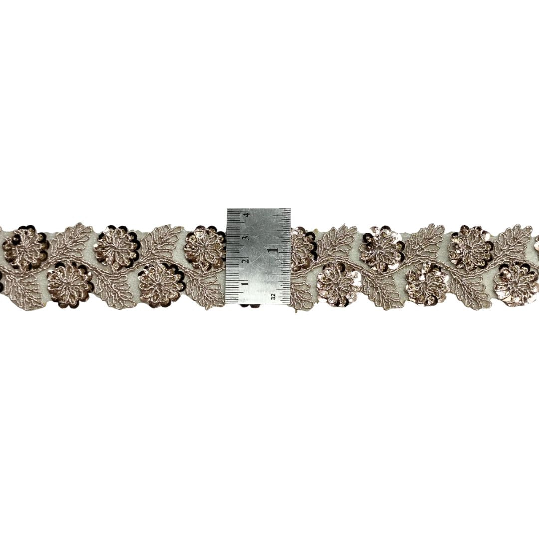 Decorative lace trim with a ruler for scale on a white background
