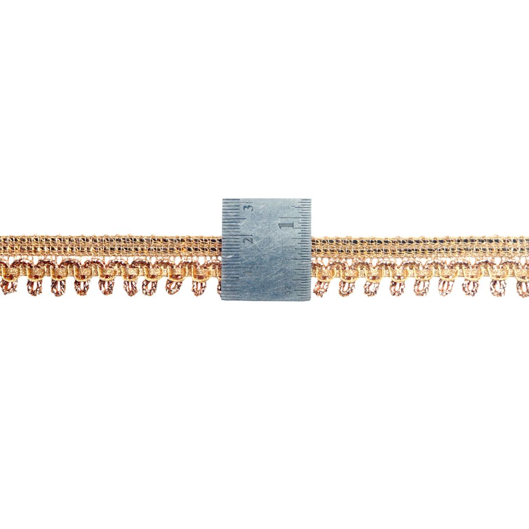 Gold fringe trim with a ruler for scale on a white background