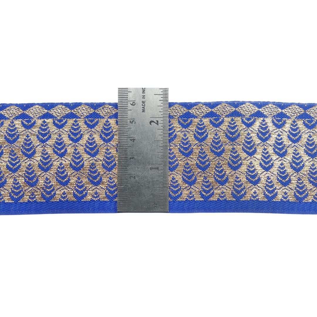 Blue and gold patterned ribbon with a ruler for scale on a white background