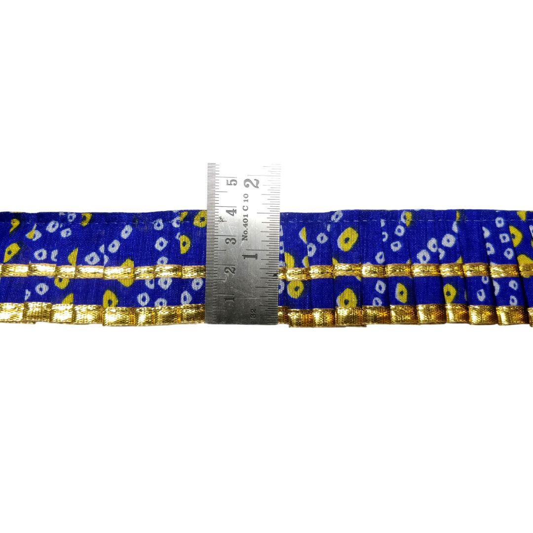 Blue ribbon with gold and yellow patterns and a measuring tape for scale on a white background