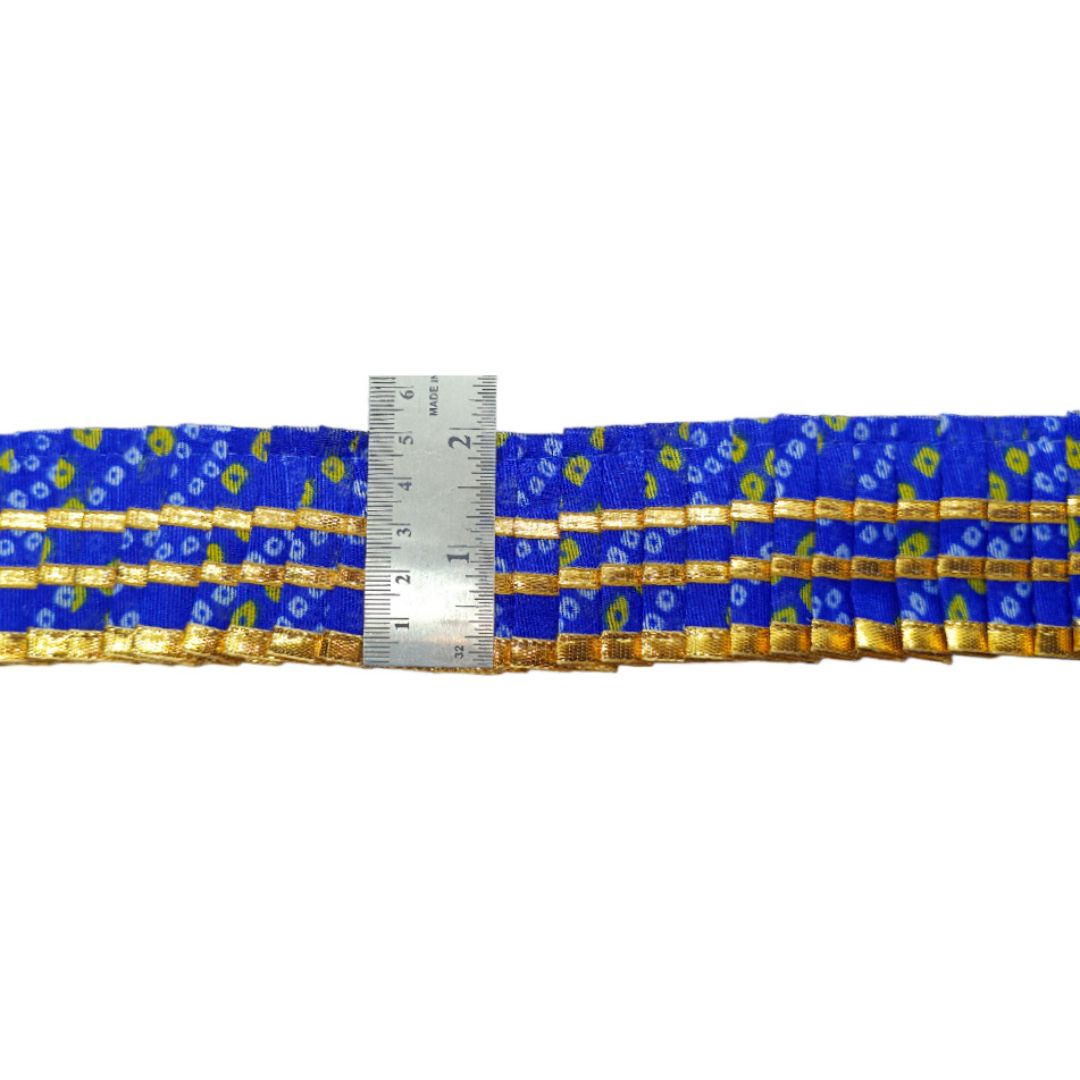 Blue and gold patterned belt with a ruler for scale on a white background