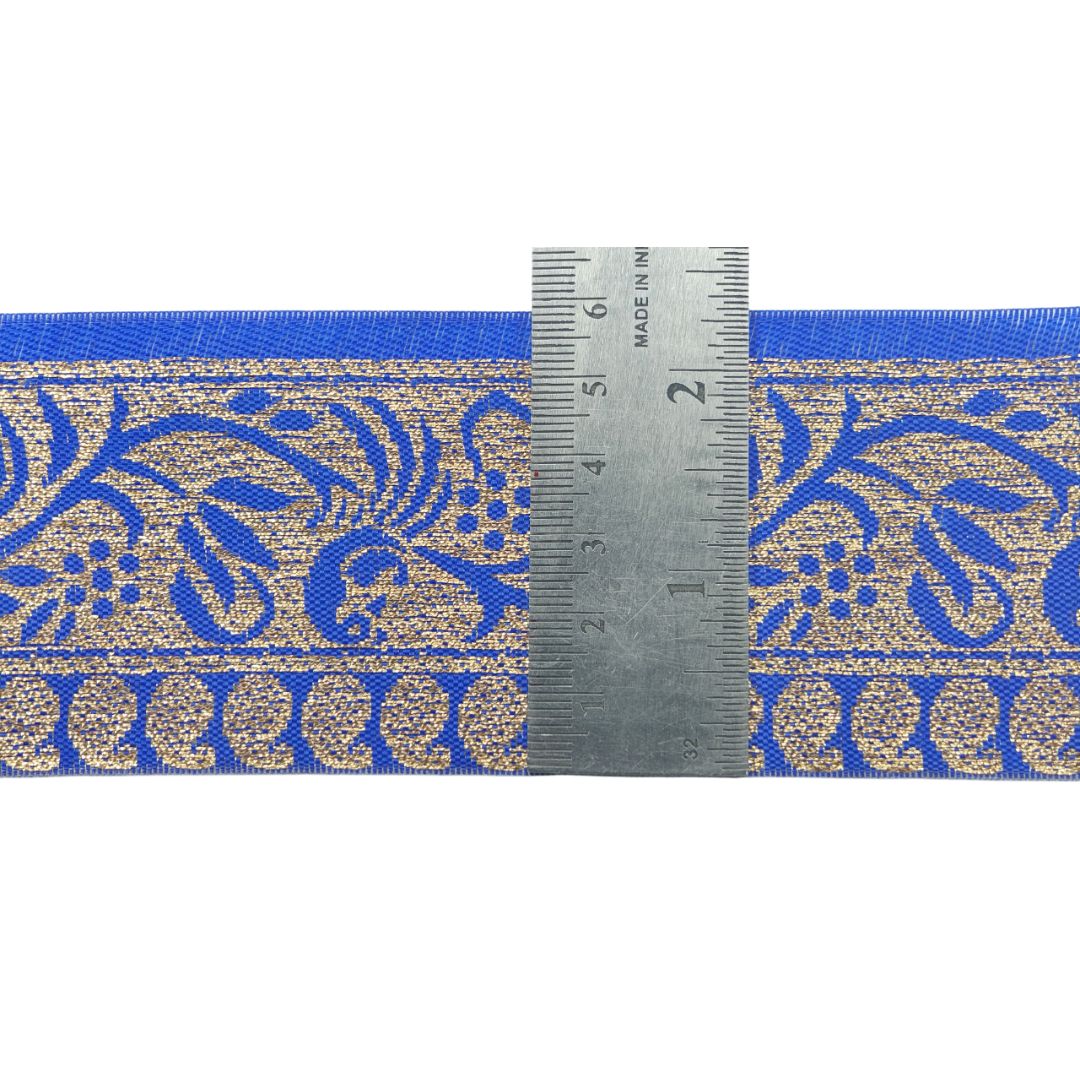 Blue and gold patterned ribbon with a ruler for scale on a white background