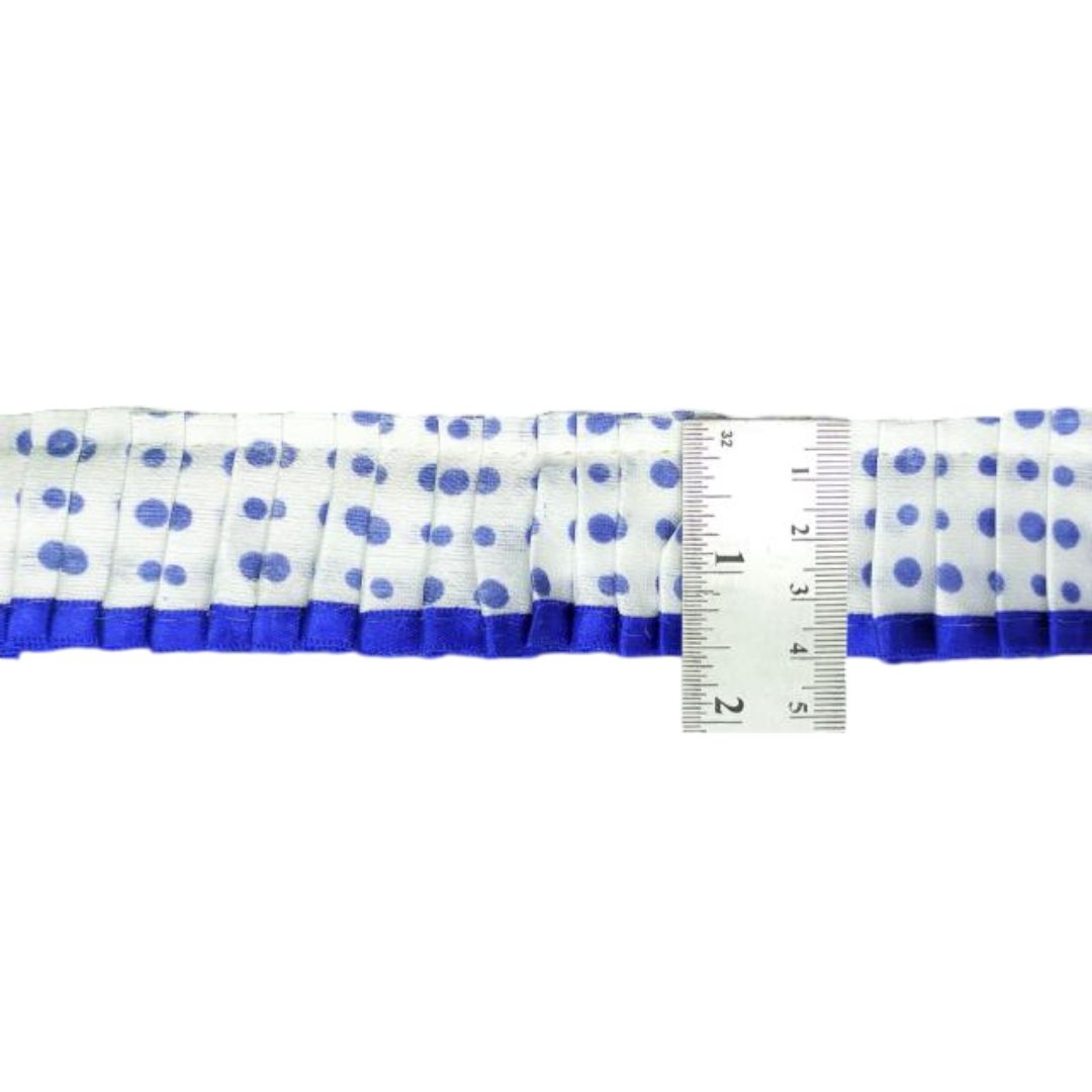 White ribbon with blue polka dots and a ruler for scale on a white background